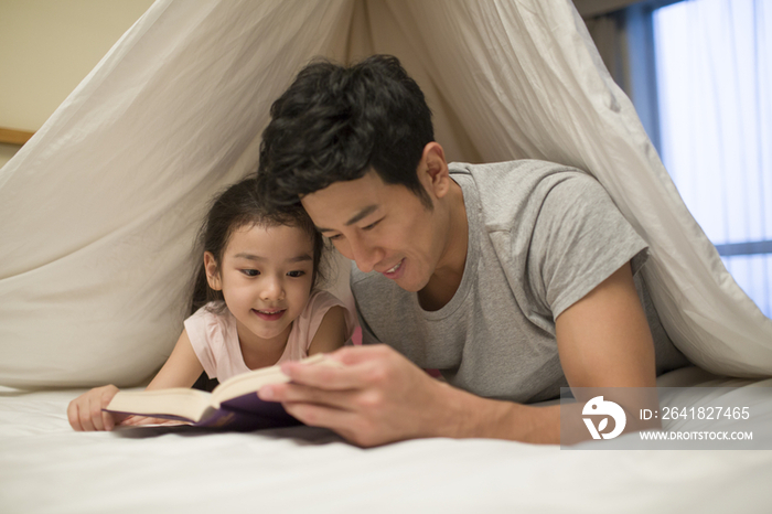 小女孩和爸爸在床上看书
