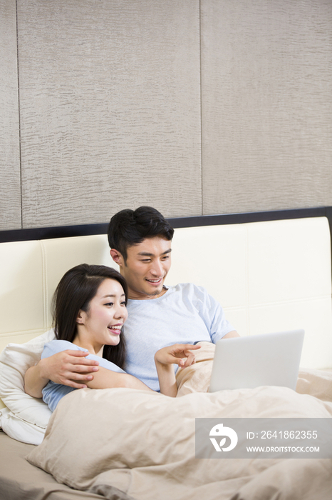 年轻夫妇在床上使用笔记本电脑