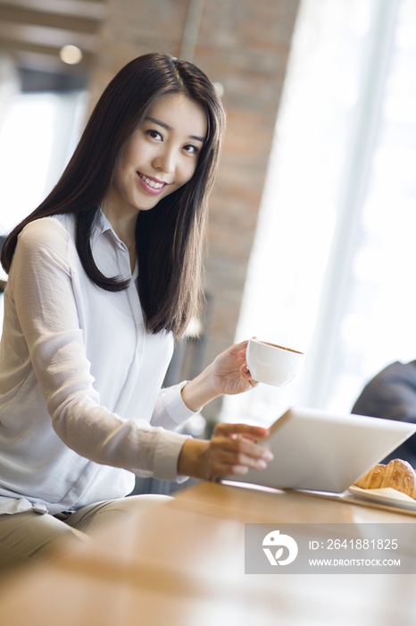 年轻女子在咖啡厅使用平板电脑