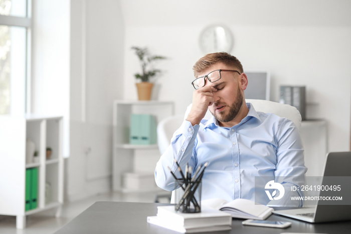 Young man suffering from headache in office