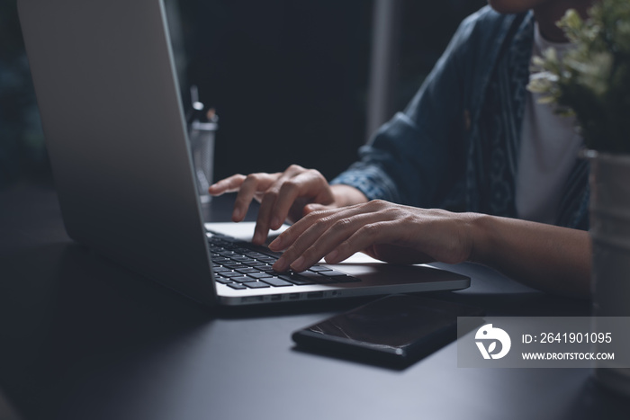 Business woman hands typing, overtime working on laptop computer from home at night