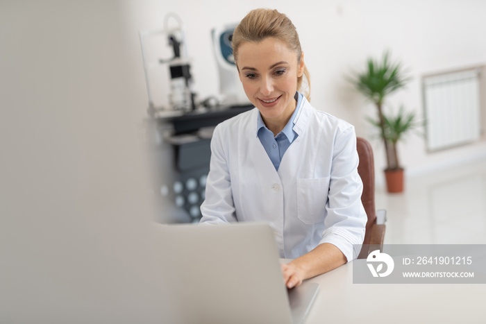 Beautiful female doctor using notebook at work