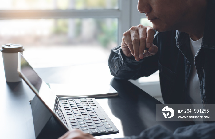 Pensive asian business man thinking while serious working on laptop computer from home office