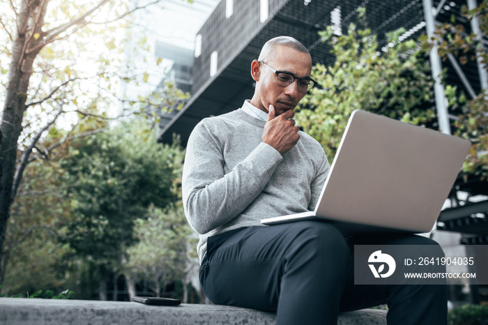 Businessman working on laptop computer sitting outdoors