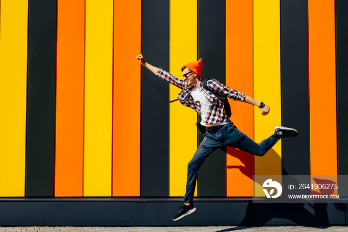 Happy young man jumping in the air, showing a superman posing looking at the camera with a beaming s