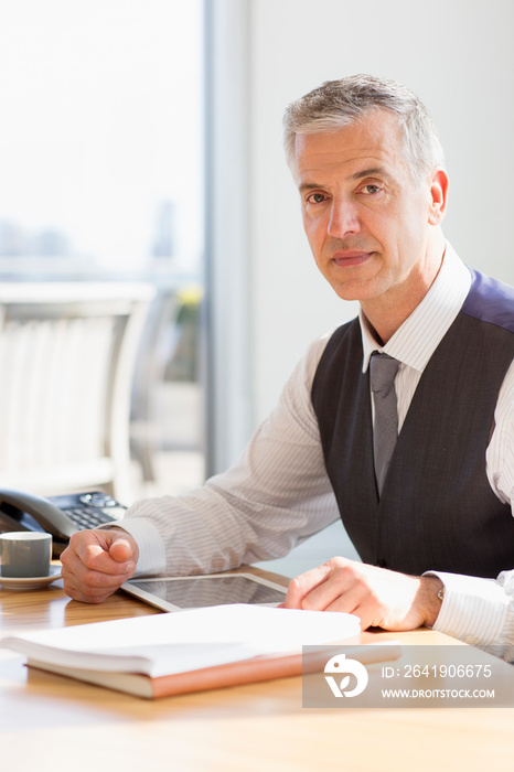 Portrait confident corporate businessman using digital tablet at desk