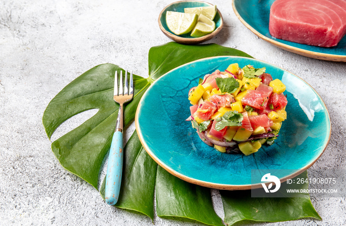 热带风味美食金枪鱼芒果沙拉酒石配香菜和紫色洋葱。在蓝色盘子里，热带