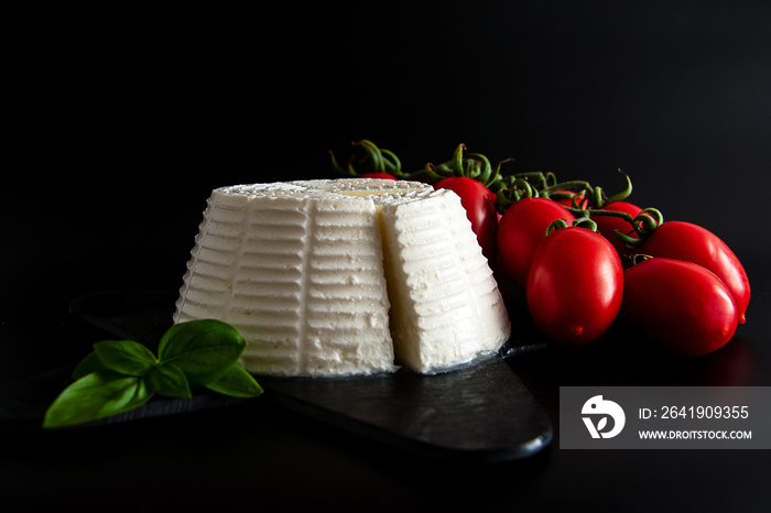 Front view view of fresh ricotta cheese with basil and cherry tomatoes on black plate italian food c