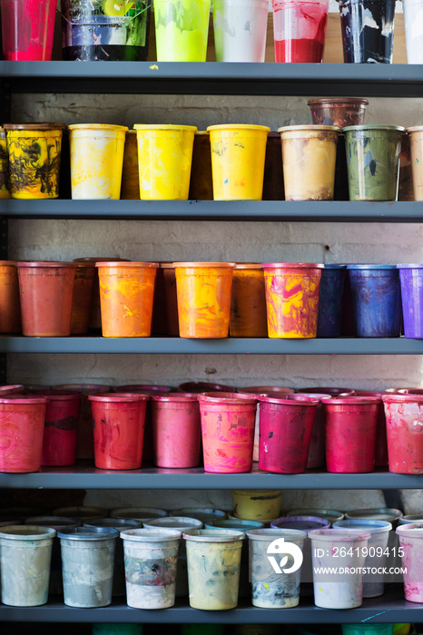 Paint cans arranged on shelf in workshop