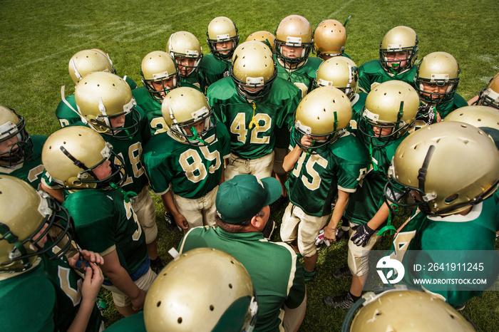 American football team talking with coach in field