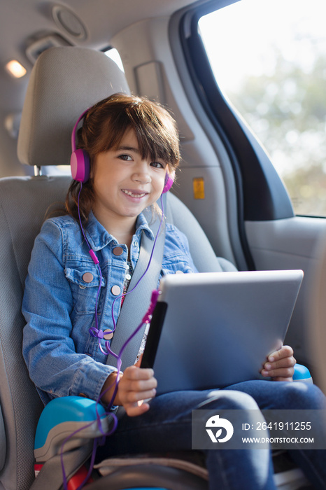 Portrait happy girl with digital tablet and headphones in car