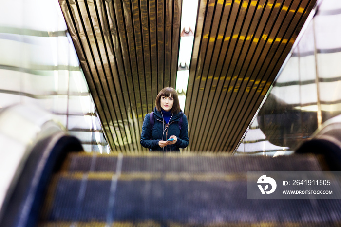 Young woman listening to music in subway station