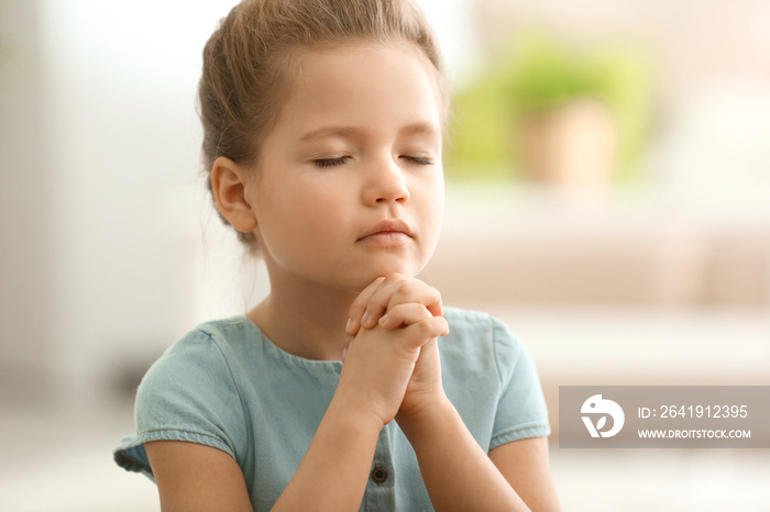 Cute little girl praying at home