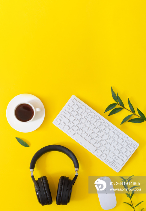 带无线耳机、笔记本电脑、鼠标、咖啡杯和平板电脑的黄色桌面俯视图