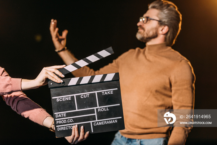 selective focus of mature actor performing role with clapboard in front