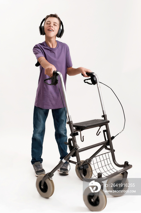 Full length shot of teenaged disabled boy with cerebral palsy in headphones listening to music, taki