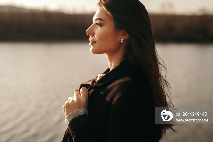 Dreamy stylish woman standing near lake