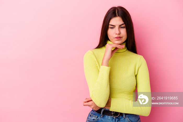 Young caucasian woman isolated on pink background looking sideways with doubtful and skeptical expre