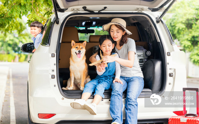 Happy family with Shiba inu dog near car outdoors. A family with a mother, daughter and son playing 