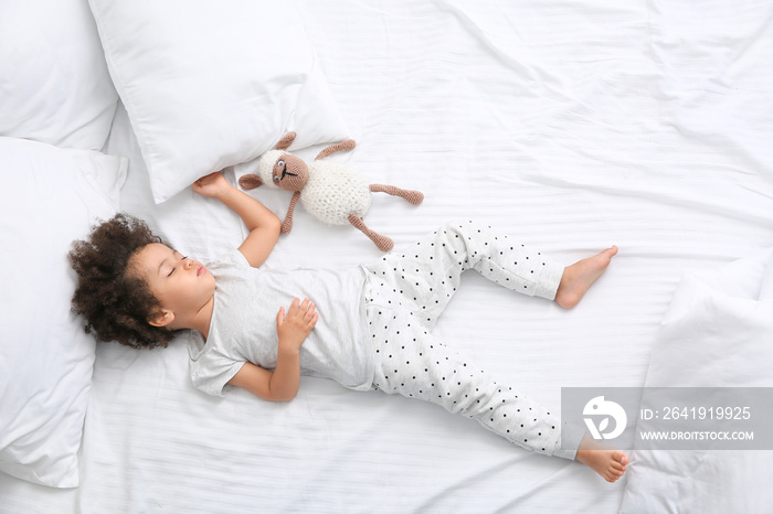 Little African-American girl with toy sleeping in bed