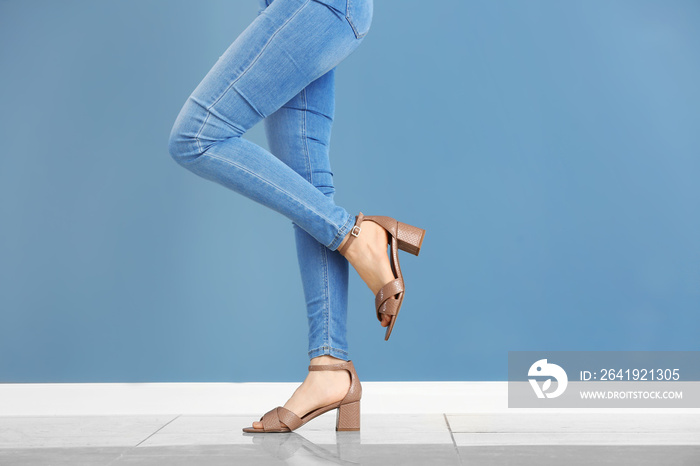 Young woman in stylish shoes against color wall