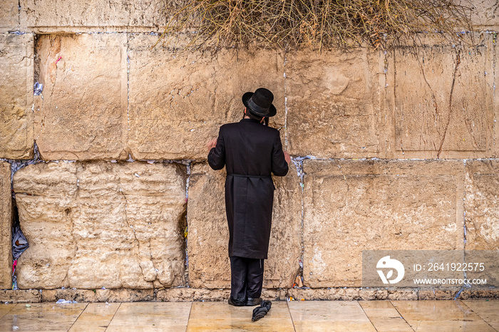 Believing Jew pray near the wall of crying in a big black hat