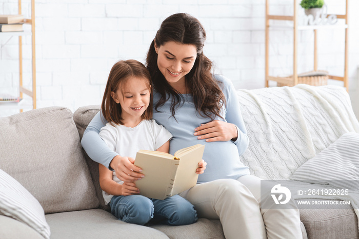 学龄前女孩和她的准妈妈正在读一本激动人心的书