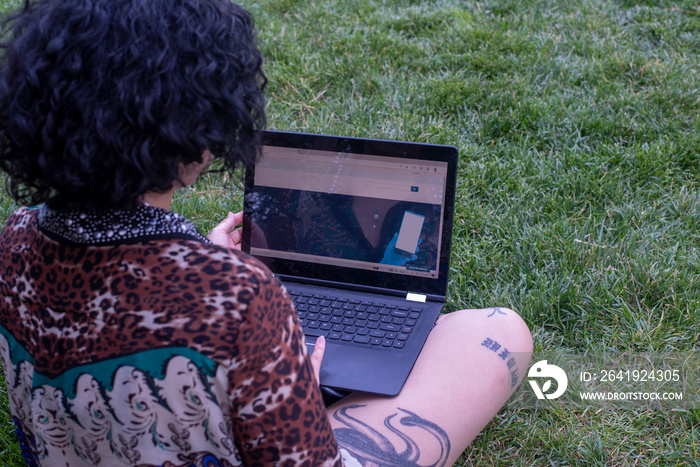 Woman using laptop on lawn�in park