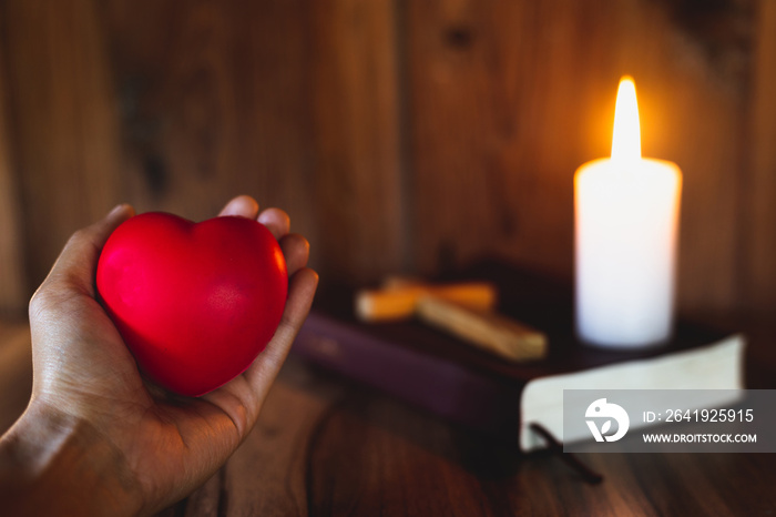 The heart symbol on a womans hand A candle lit up the scriptures. Pray for Gods blessing with fait