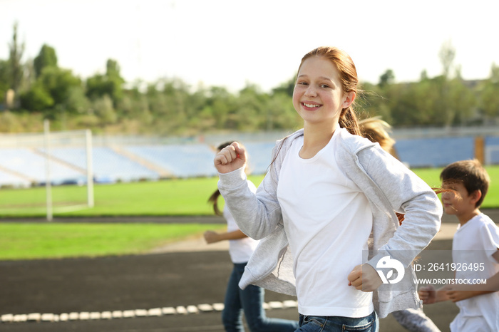 Sporty children running on track at stadium