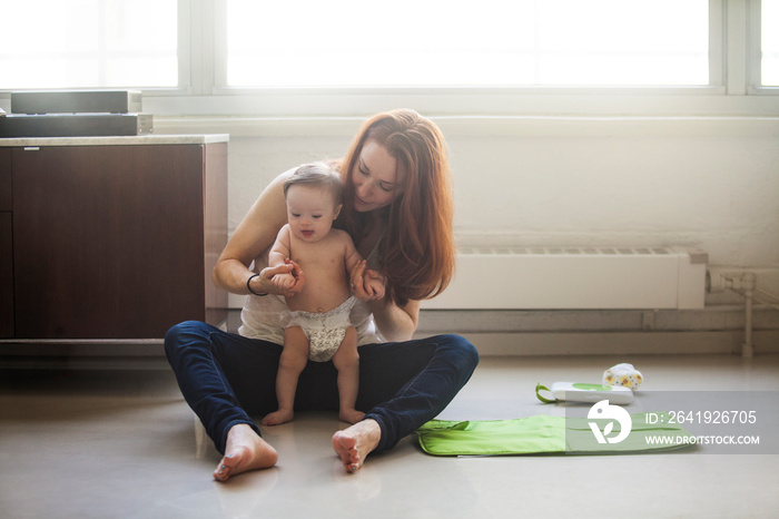 Mother changing baby girls (6-11 months) diaper