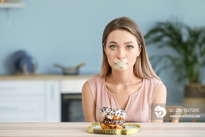 压力重重的女人，嘴巴被胶带封住，厨房里有美味的甜甜圈。饮食概念