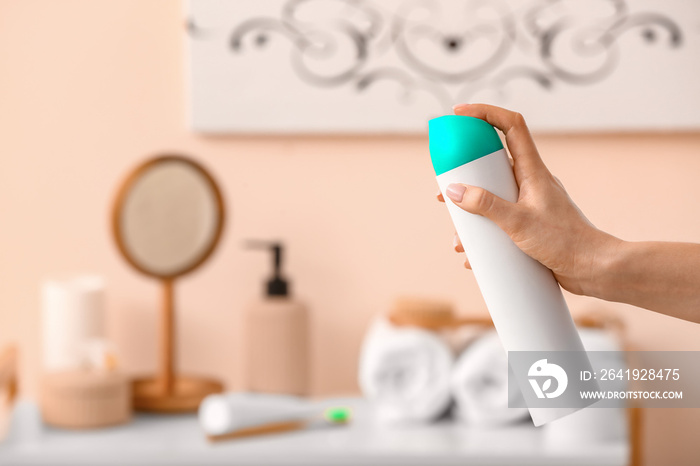 Woman spraying air freshener in room