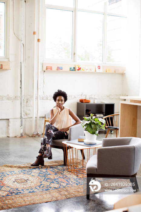 Portrait of young woman sitting in armchair at home