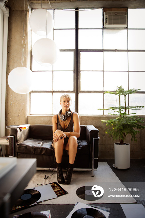 Portrait of young woman sitting on sofa with headphones