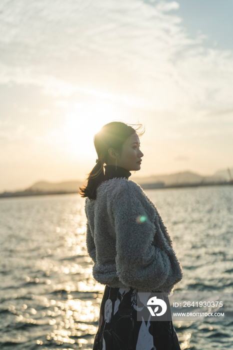 冬の夕暮れの海にいる女性