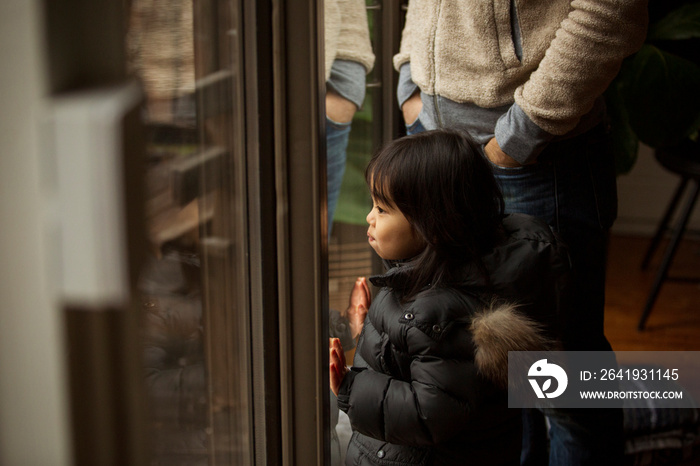 Midsection of father standing with cute daughter looking through window at home