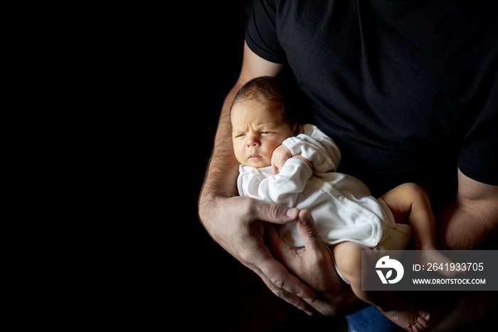 Father holding his 15 days old son in his hand on black background