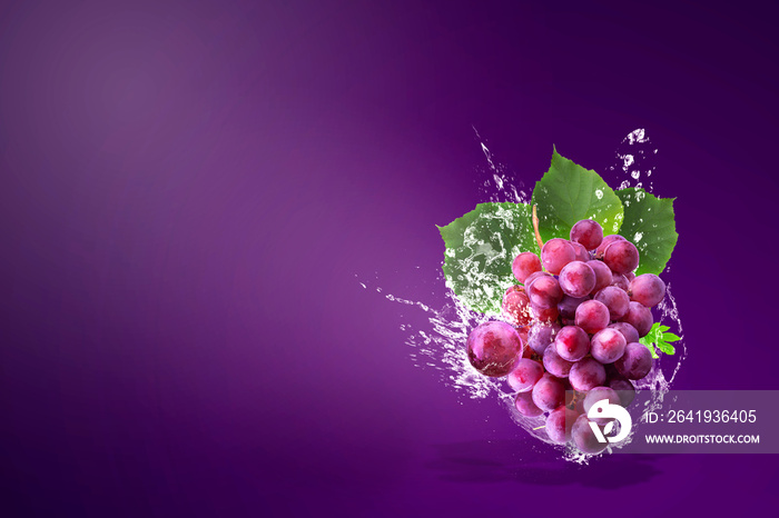 Water splashing on Fresh Red Grapes over red background.