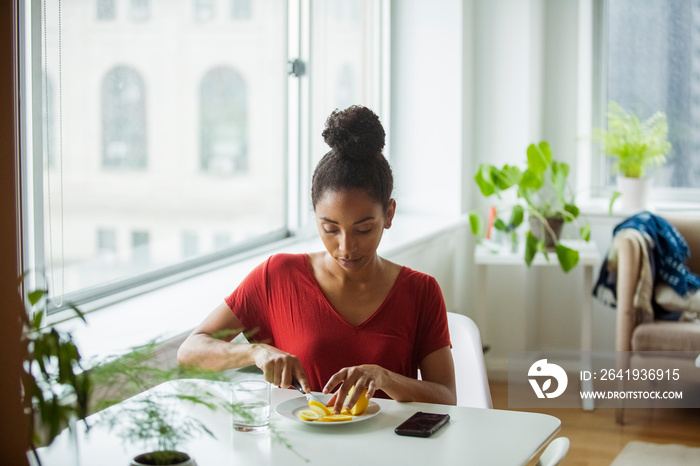 家里桌子上的女人用饮料和智能手机切柠檬