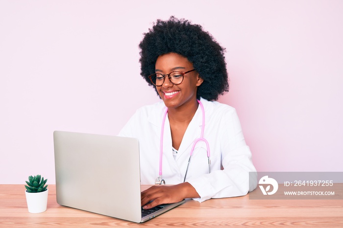 Young african american woman wearing doctor stethoscope working using computer laptop looking positi