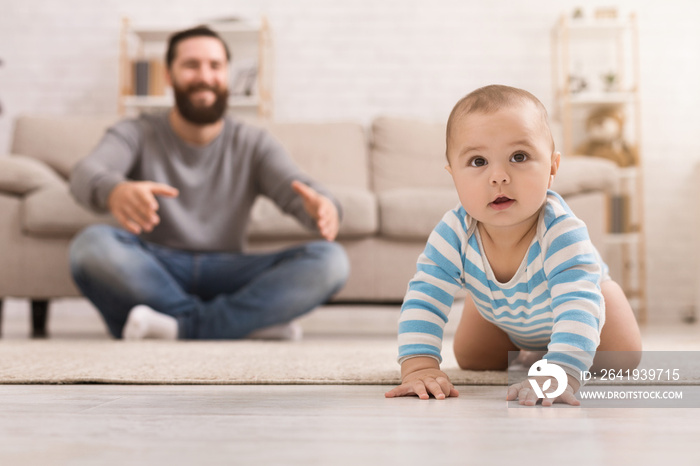 Adorable baby boy crawling on floor with dad