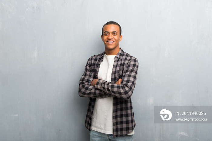 Young african american man with checkered shirt keeping the arms crossed in frontal position