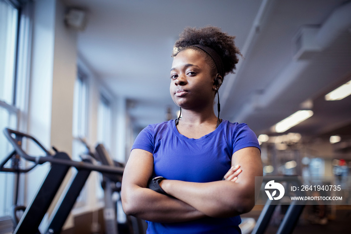 Portrait of serious female athlete with arms crossed standing in health club