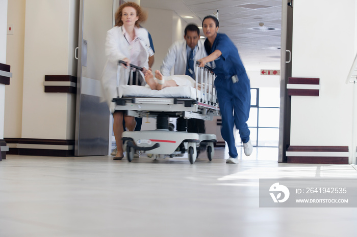 Doctors and nurse rushing patient on stretcher in hospital corridor