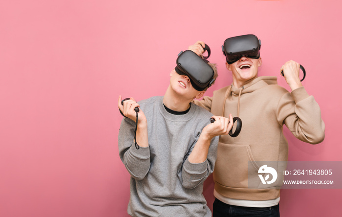 两个兴高采烈的朋友站在粉红色的背景上，头上戴着VR头盔，手里拿着控制器