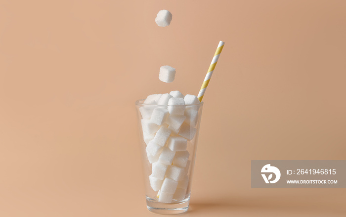 Dropping of sugar cubes into glass on color background