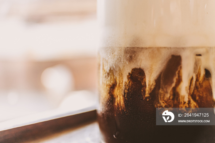 Iced coffee with milk foam and spice on top in the cafe.