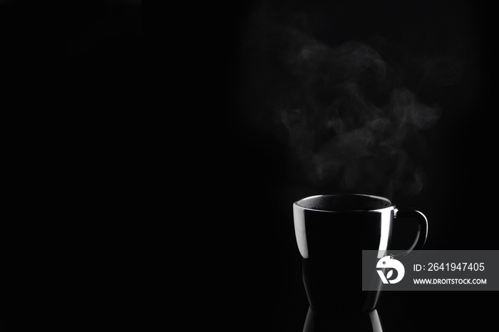 用黑色马克杯蒸咖啡或茶，深色背景反光