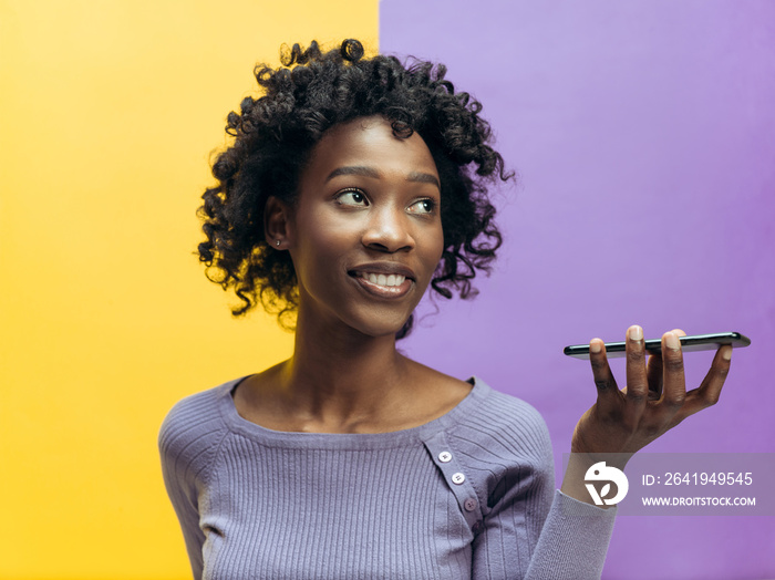 Indoor portrait of attractive young black african woman isolated on color background, holding blank 